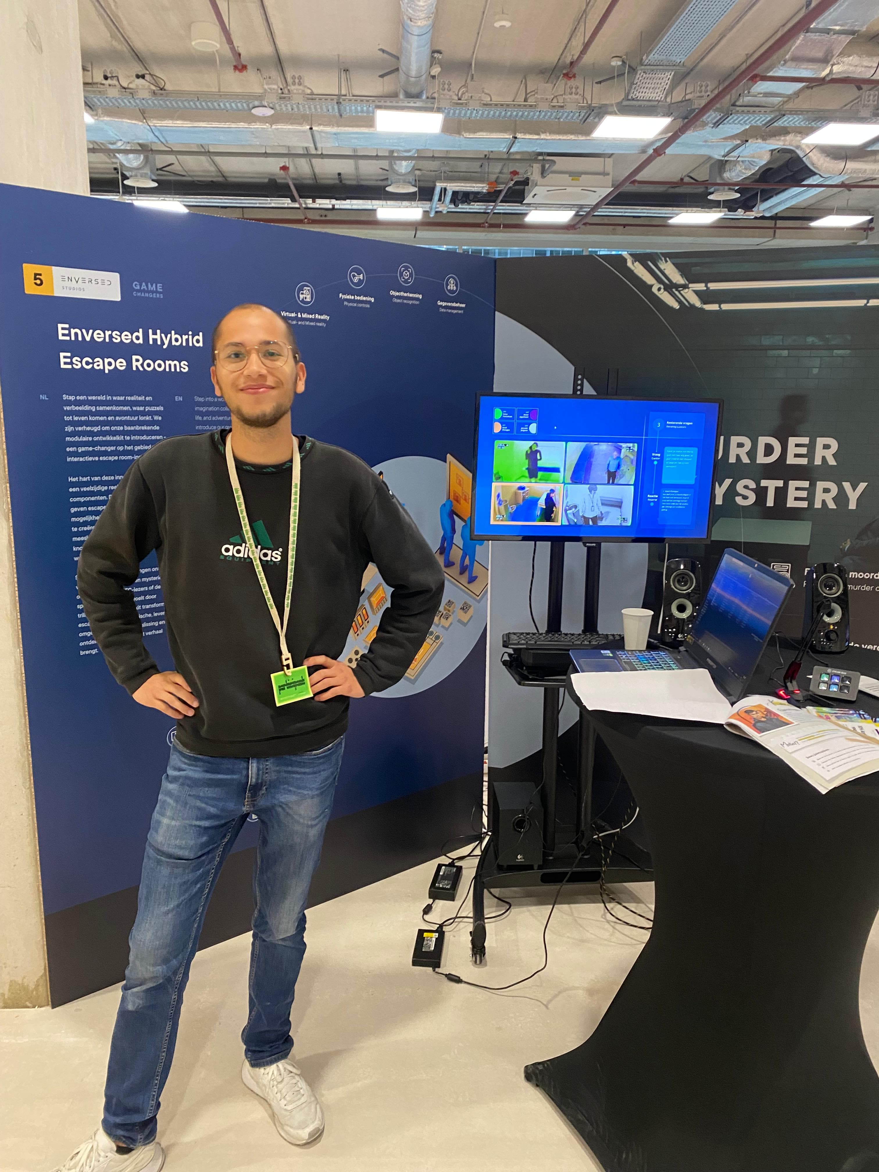 Me at the Enversed stand at Dutch Design Week 2023, next to the Murder Mystery setup: an external monitor showing the four suspects, speakers, a microphone, and a Stream Deck with a button per suspect.