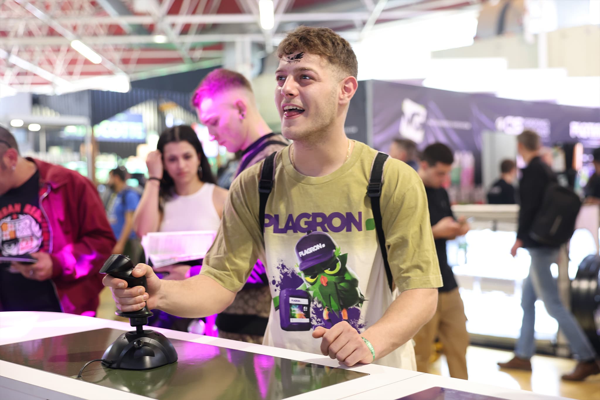 A player working the physical joystick, wearing Plagron event merch.
